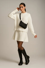 Elegant white knit sweater and skirt set for women with black boots and shoulder bag